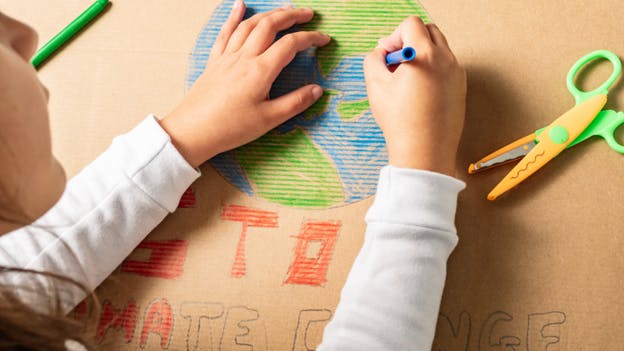 Hands of child drawing a globe with crayons