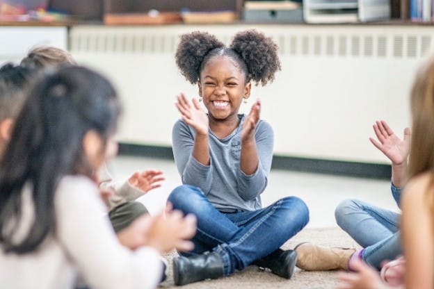 Happy girl clapping and smiling in a classroom