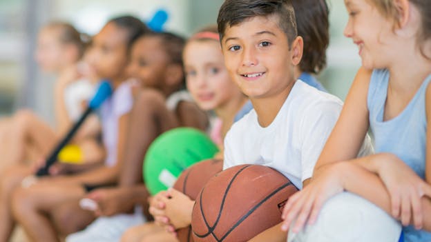 Photo of kids in a gym holding different kinds of gym equipment